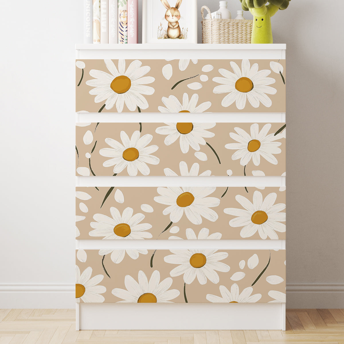 Vit IKEA MALM-byrå med fyra lådor och dekorfolie med stora vita prästkragar mot en beige bakgrund.