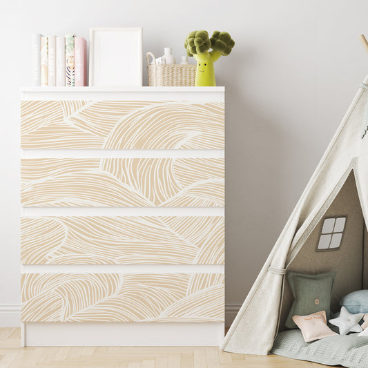 Vit IKEA MALM-byrå med fyra lådor och dekorfolie med ett abstrakt mönster av böljande beige och vita linjer.
