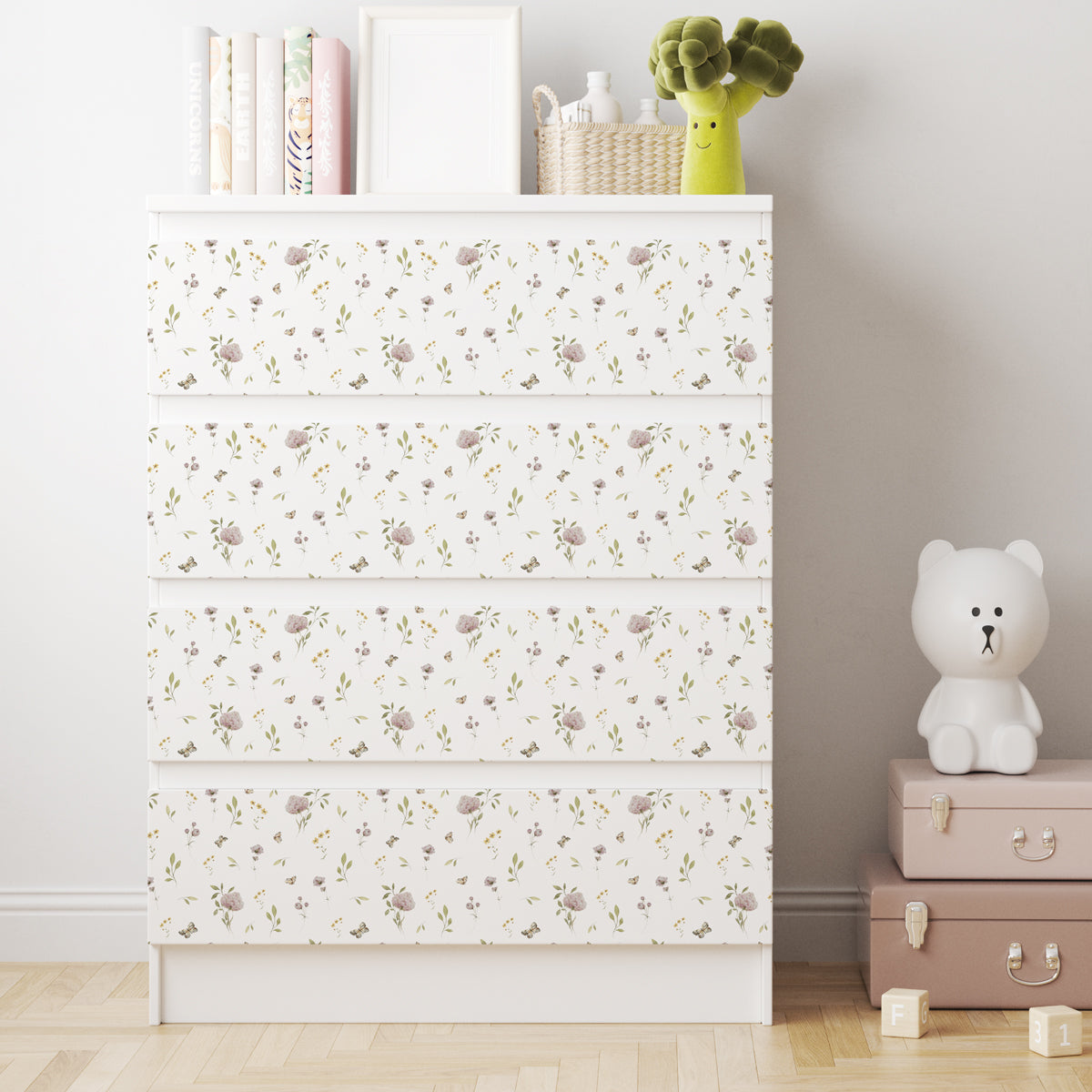 Vit IKEA MALM-byrå med fyra lådor och dekorfolie med små blommor, gröna blad och fjärilar i mjuka färger.
