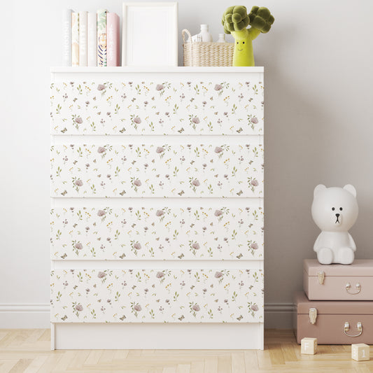 Vit IKEA MALM-byrå med fyra lådor och dekorfolie med små blommor, gröna blad och fjärilar i mjuka färger.
