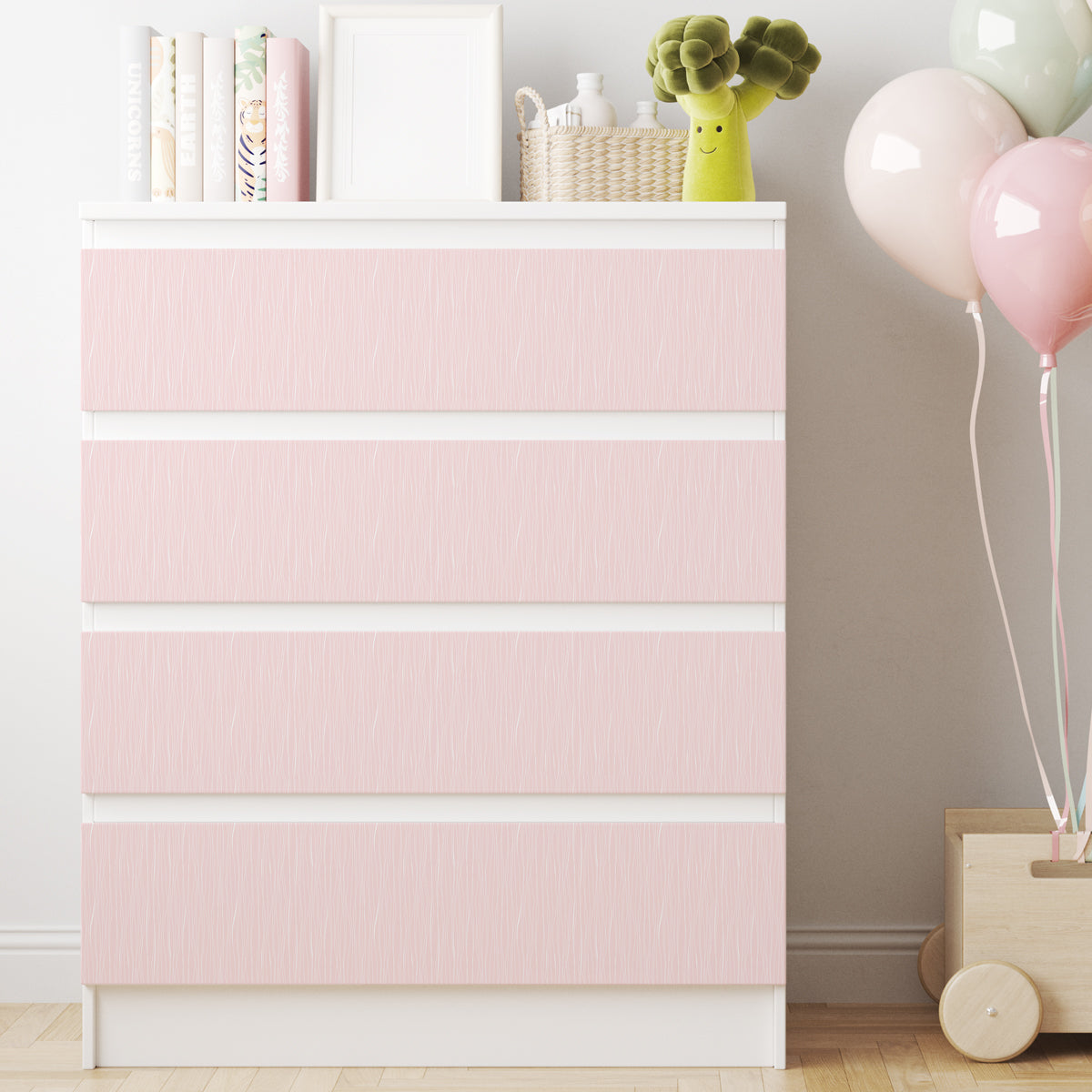 Vit IKEA MALM-byrå med fyra lådor och ljusrosa dekorfolie med ett diskret mönster av tunna vita linjer.
