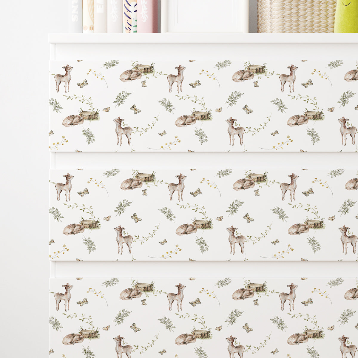 Vit IKEA MALM-byrå med dekorfolie med rådjur, gröna blad och små gula blommor.
